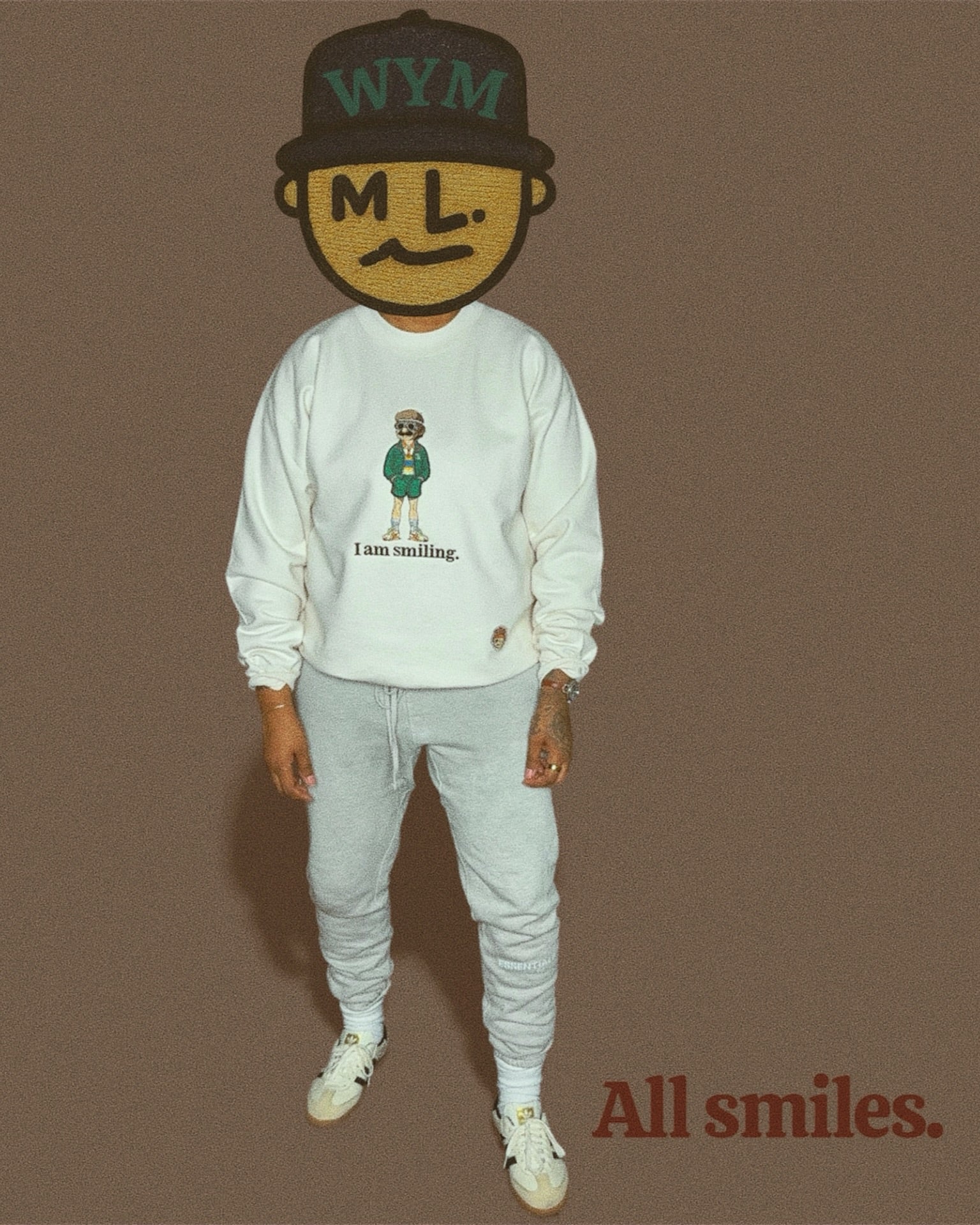 Person wearing an oatmeal colored sweatshirt and pants with a graphic design, standing against a brown background.