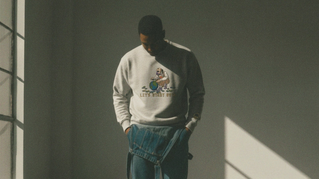 Person wearing an ash gray sweatshirt with a graphic design in a dimly lit room.