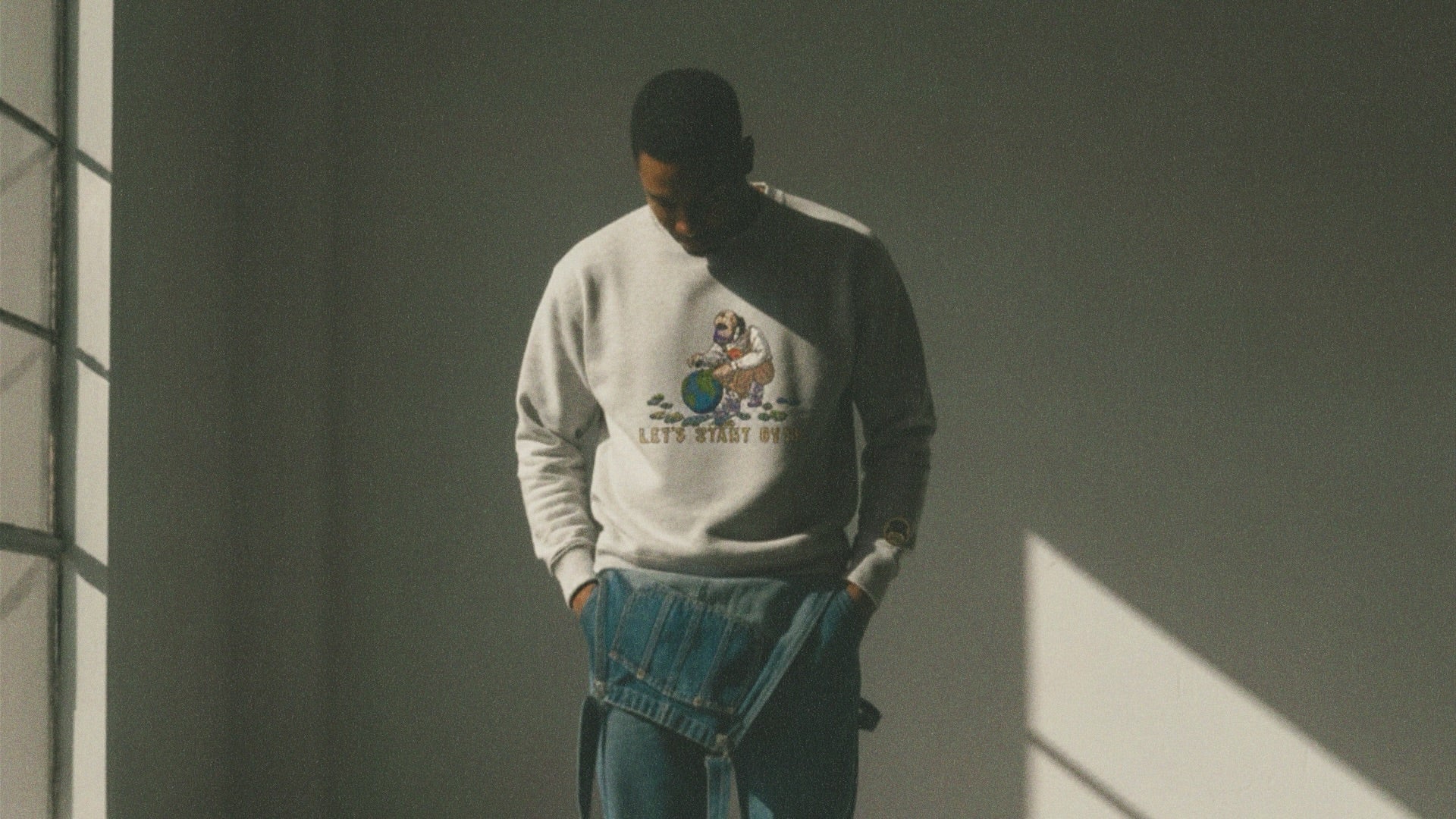 Person wearing an ash gray sweatshirt with a graphic design in a dimly lit room.